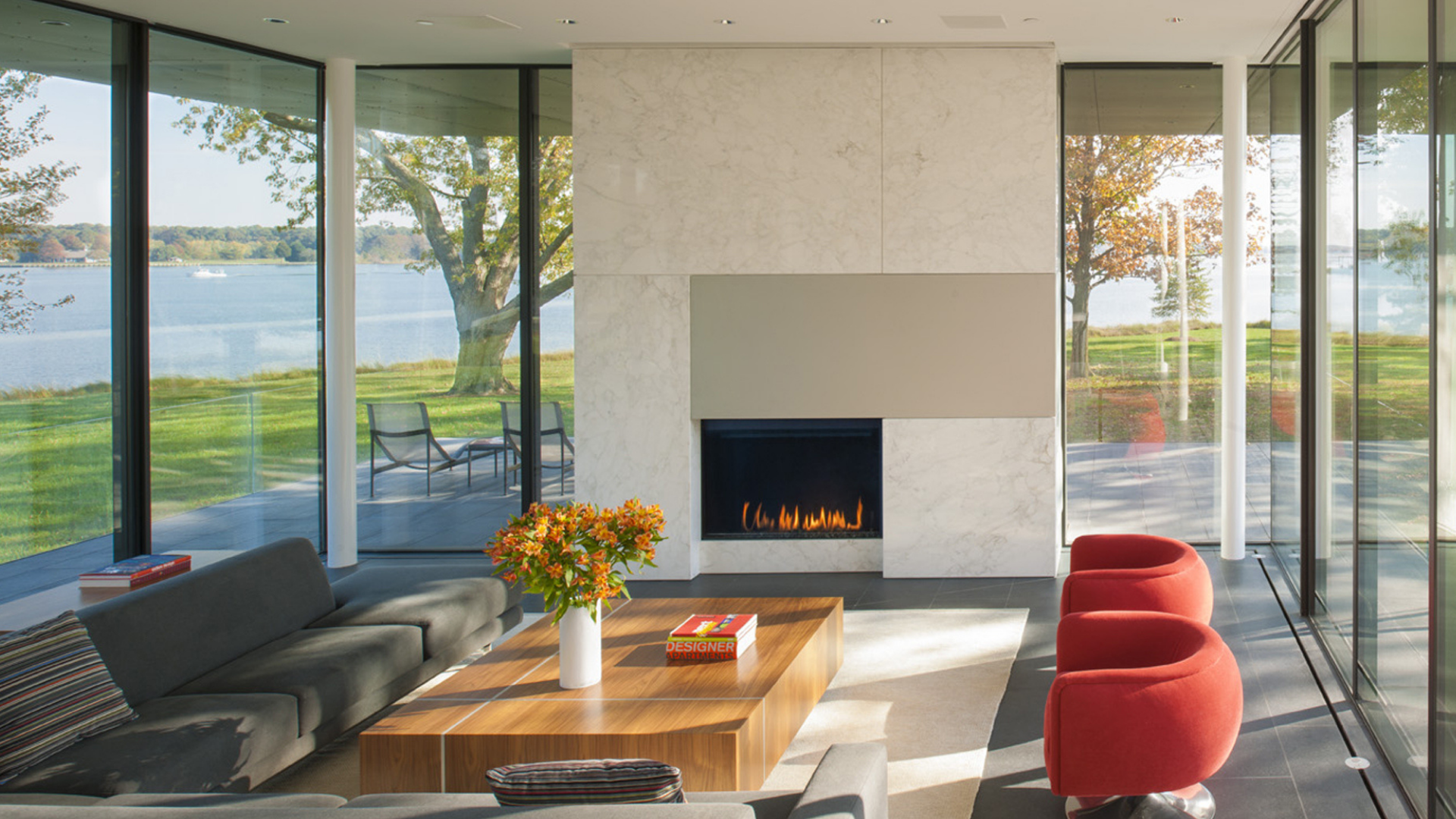 Modern lakefront living room with floor-to-ceiling windows and fireplace
