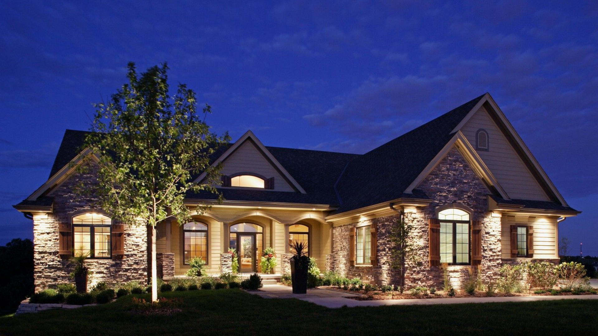 Elegant stone and stucco home illuminated at twilight
