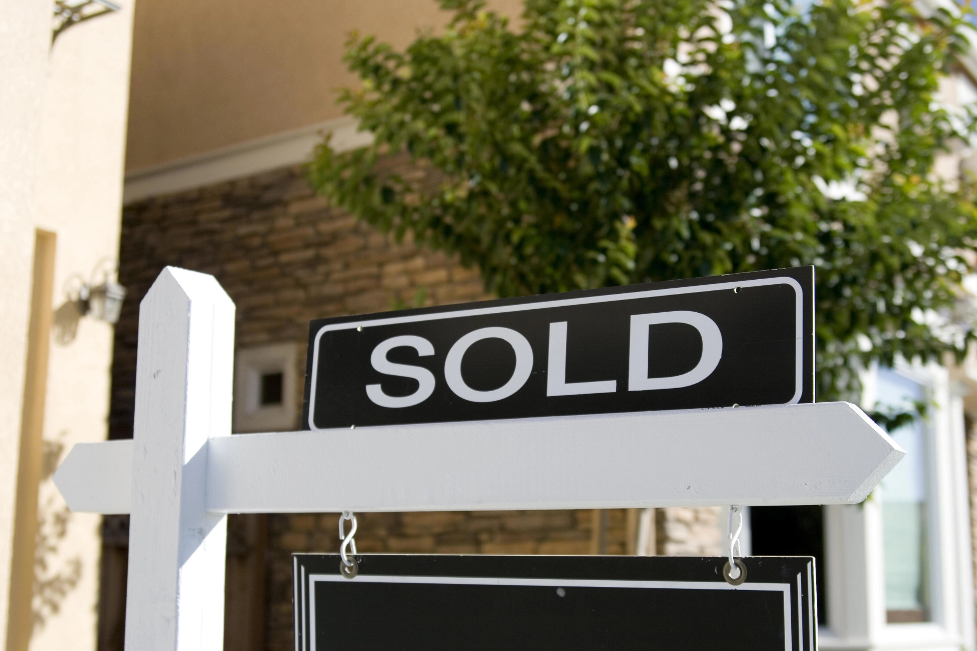 Black and white SOLD real estate sign in front of a home
