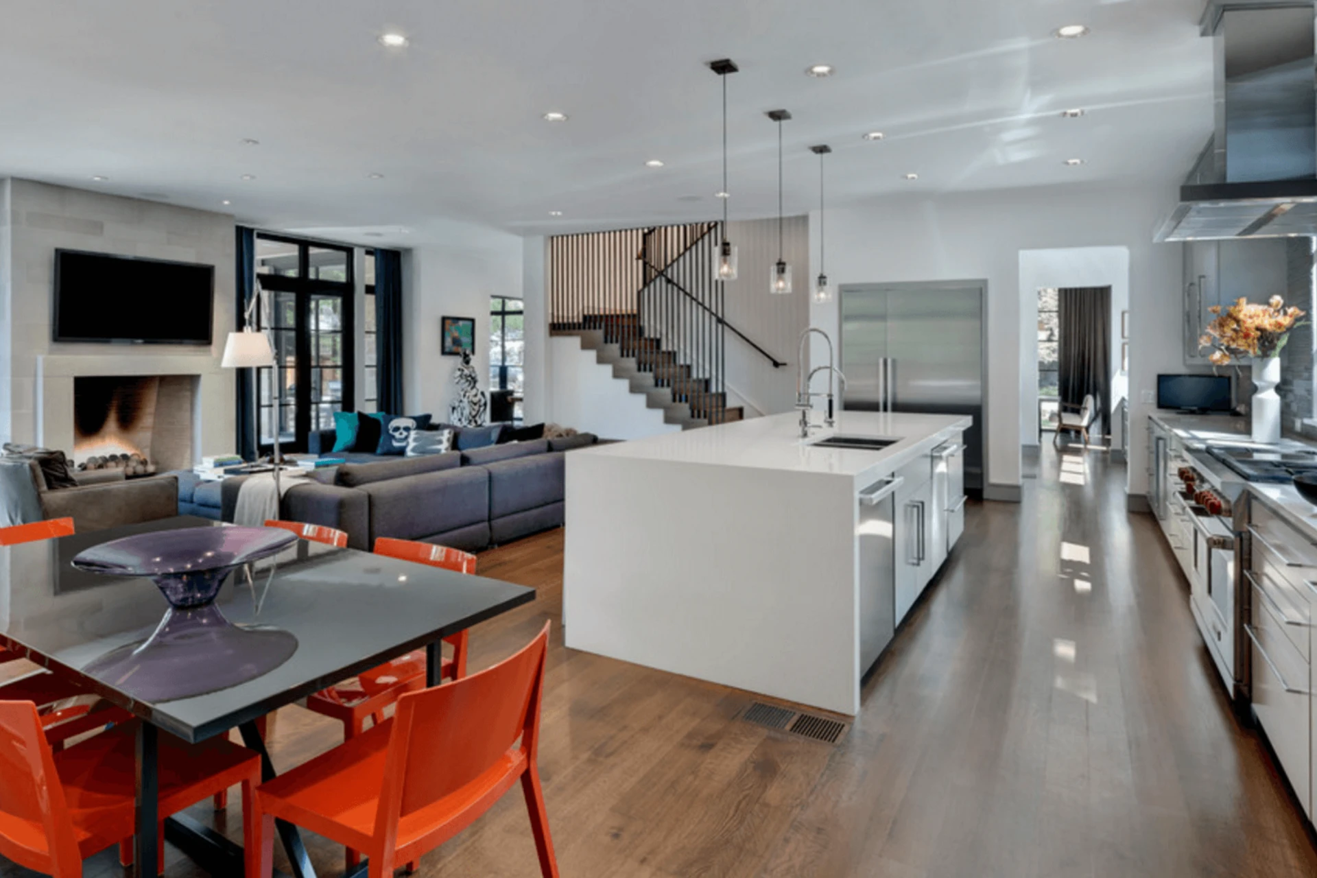Open-concept living, dining, and kitchen space with white island and hardwood floors